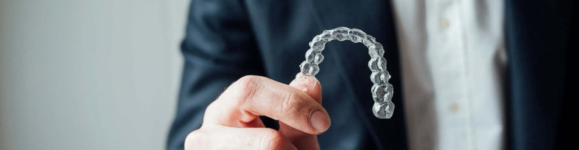 Hand holding clear aligner.